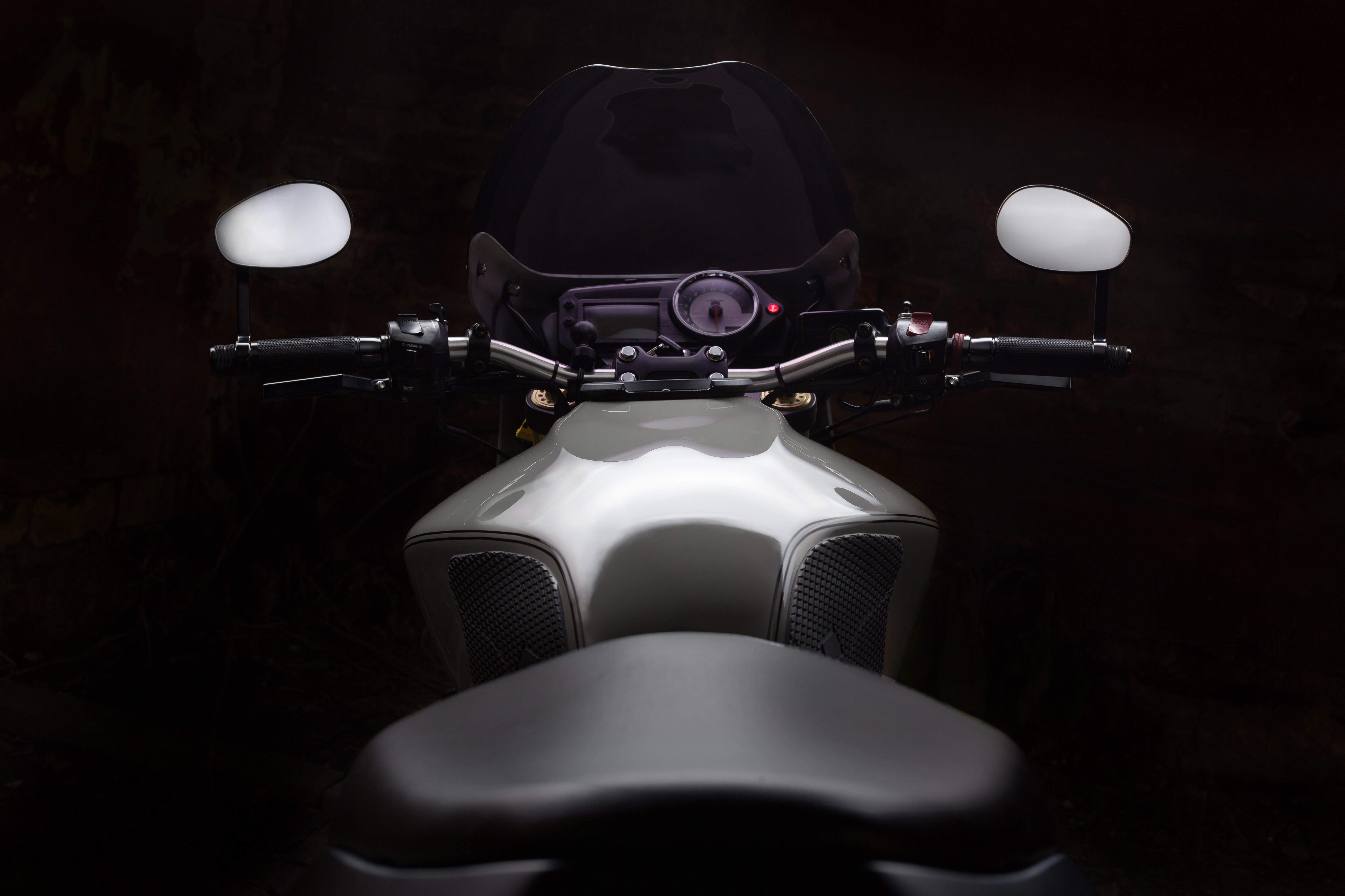 Custom caferacer motorbike on dark background with its headlight on